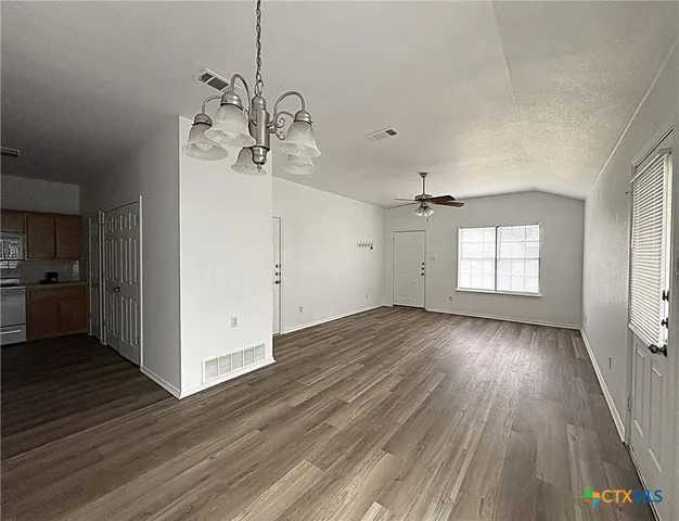 an empty room with wooden floor ceiling fan and windows