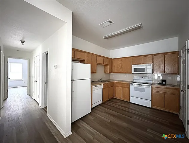 a kitchen with a refrigerator stove and wooden floors