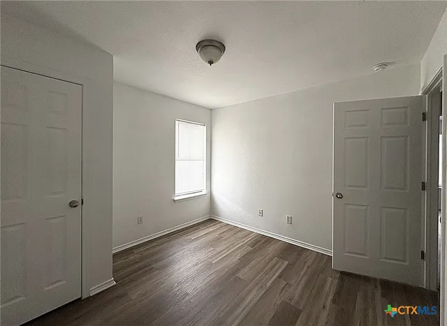 an empty room with wooden floor and window