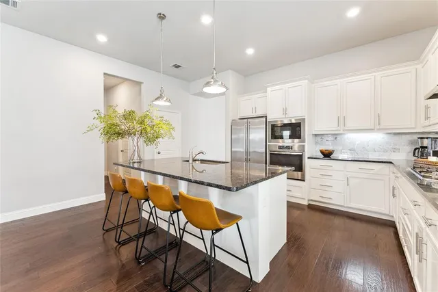 a kitchen with stainless steel appliances kitchen island granite countertop a stove a sink and a refrigerator