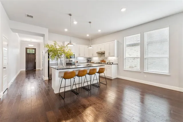 a kitchen with stainless steel appliances granite countertop a refrigerator a sink dishwasher and a stove with wooden floor