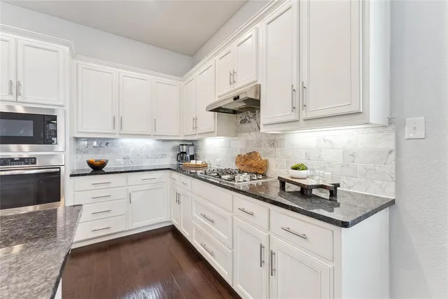 a kitchen with granite countertop white cabinets and white appliances