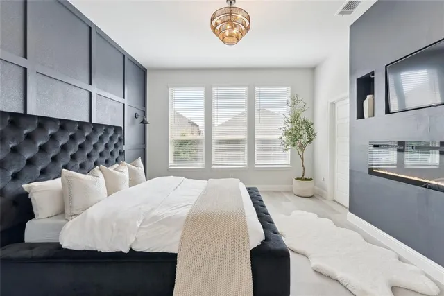 a bedroom with a bed and a lamp on dresser next to a window