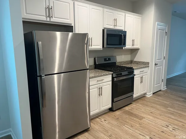 a kitchen with stainless steel appliances a refrigerator stove and microwave