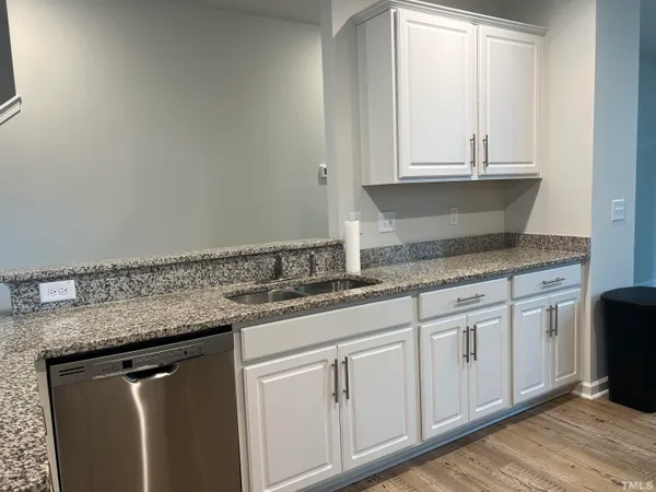 a kitchen with granite countertop white cabinets and a sink