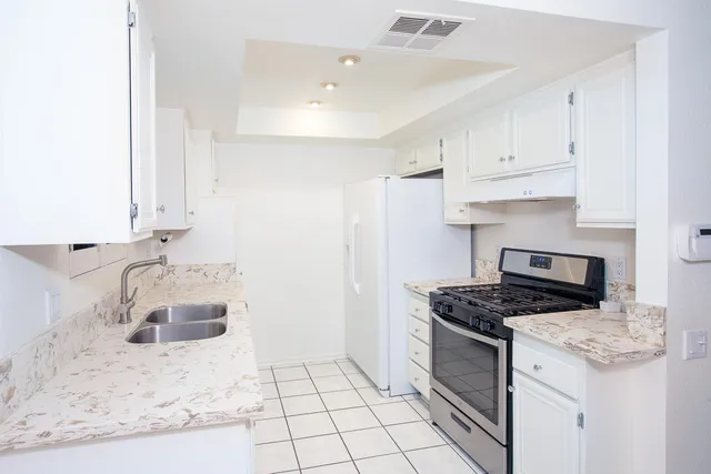 a kitchen with granite countertop a sink a stove and cabinets