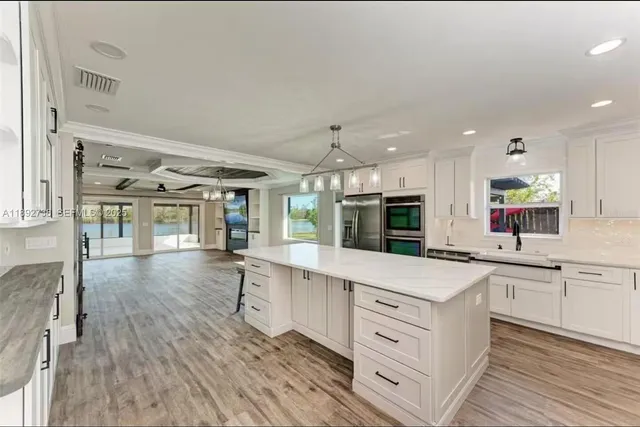 a kitchen with kitchen island a counter top space a sink stainless steel appliances and cabinets