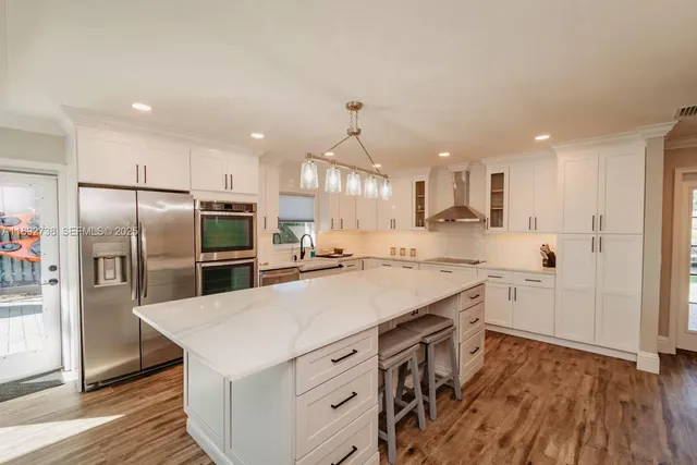 a large white kitchen with lots of counter space a sink and appliances