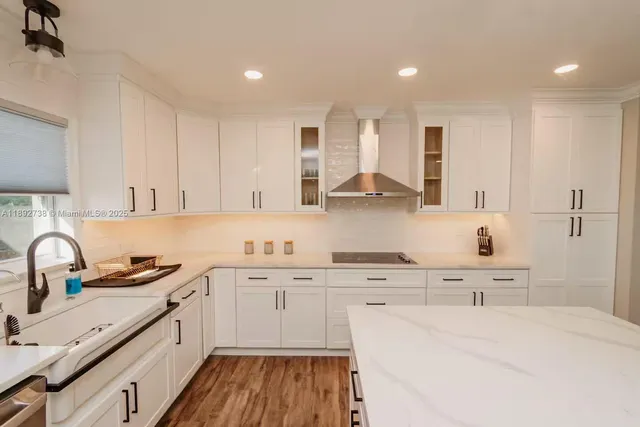 a kitchen with kitchen island a sink a stove a refrigerator and white cabinets with wooden floor
