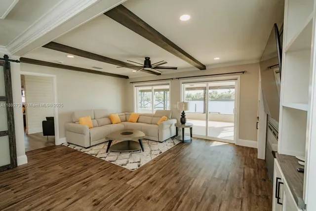 a living room with furniture a large window and wooden floor