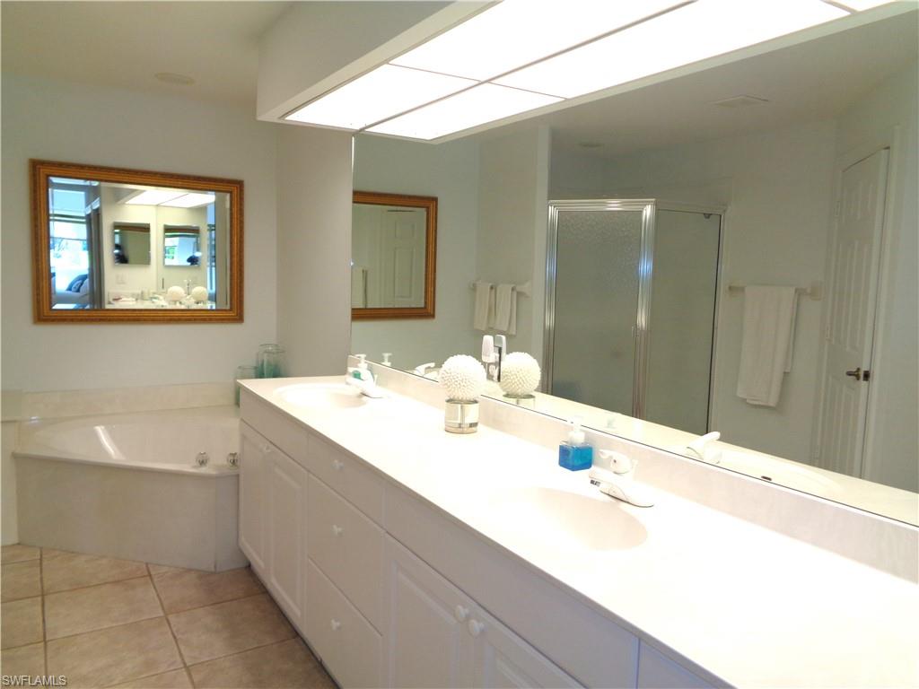 515 Laguna Royale Boulevard, Unit 102 Naples, FL 34119 - Photo 20 of 28 Bathroom featuring tile patterned flooring, a sink, and a stall shower