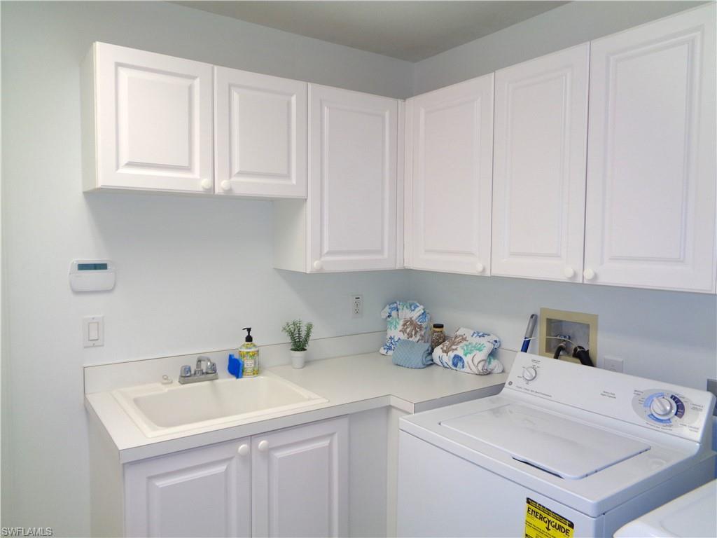 515 Laguna Royale Boulevard, Unit 102 Naples, FL 34119 - Photo 25 of 28 Laundry room featuring washer and clothes dryer, cabinet space, and a sink