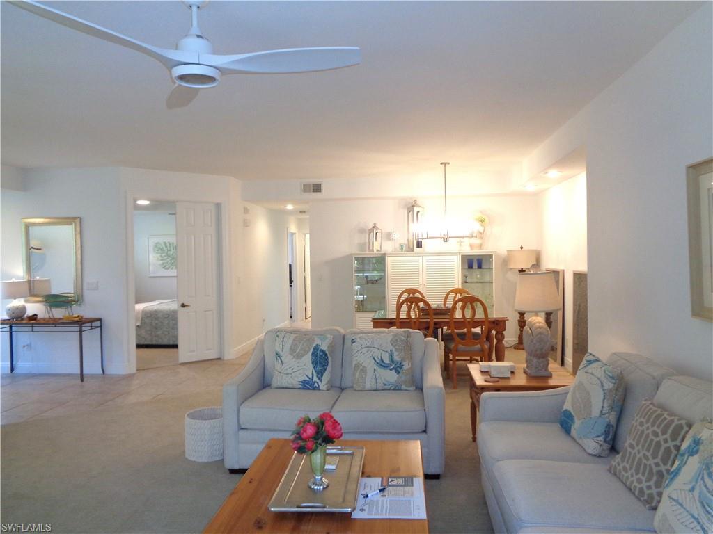 515 Laguna Royale Boulevard, Unit 102 Naples, FL 34119 - Photo 4 of 28 Living area featuring ceiling fan with notable chandelier, baseboards, and visible vents