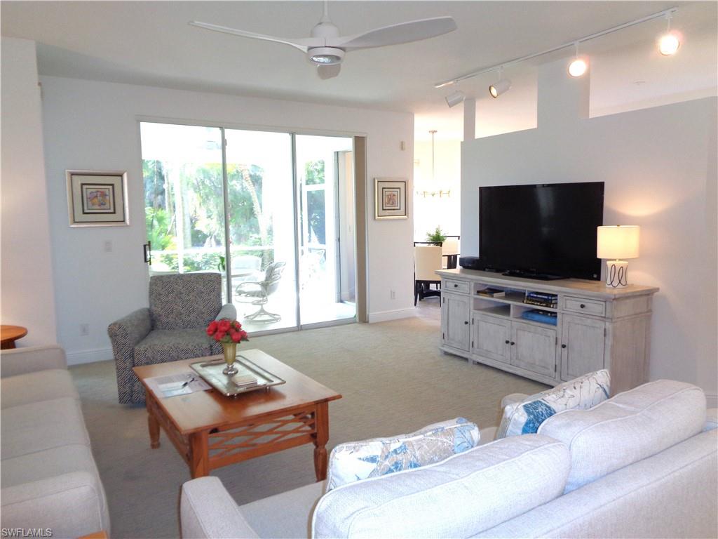 515 Laguna Royale Boulevard, Unit 102 Naples, FL 34119 - Photo 6 of 28 Living room featuring a ceiling fan, baseboards, and light colored carpet