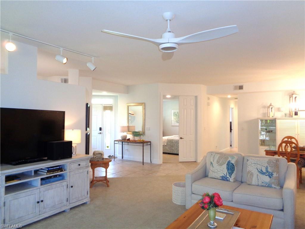 515 Laguna Royale Boulevard, Unit 102 Naples, FL 34119 - Photo 7 of 28 Living area featuring ceiling fan, visible vents, and light colored carpet