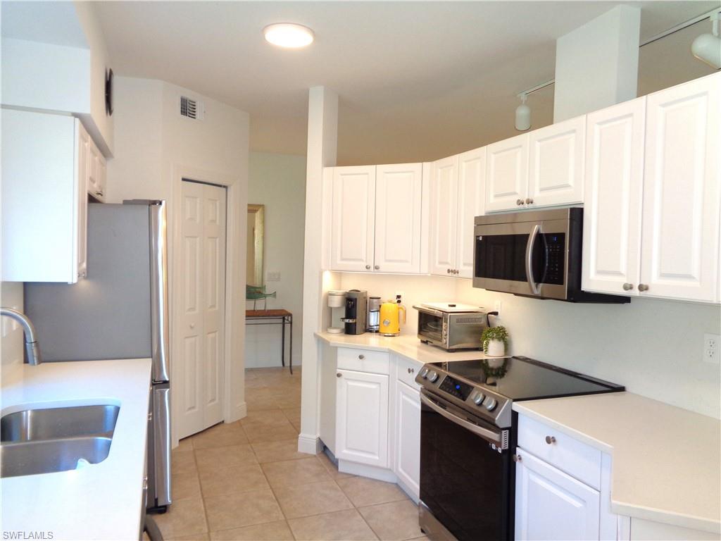 515 Laguna Royale Boulevard, Unit 102 Naples, FL 34119 - Photo 9 of 28 Kitchen featuring white cabinets, a sink, stainless steel appliances, and light tile patterned floors