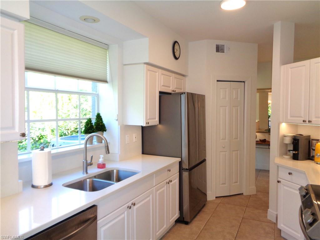 515 Laguna Royale Boulevard, Unit 102 Naples, FL 34119 - Photo 10 of 28 Kitchen with white cabinets, visible vents, light countertops, stainless steel appliances, and a sink