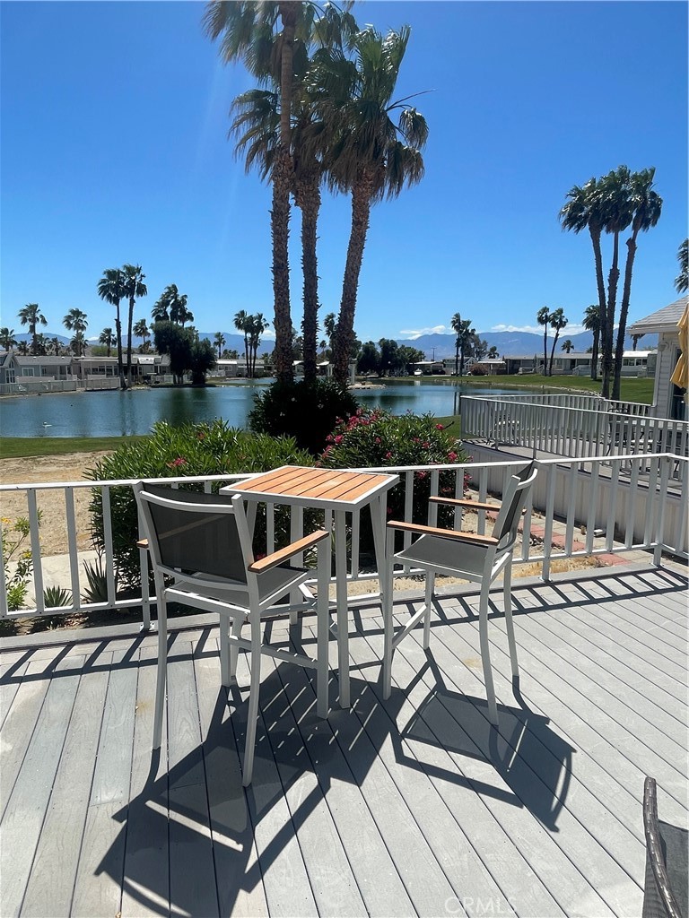 74711 Dillon Road, Unit 69 Desert Hot Springs, CA 92241 - Photo 9 of 18 a view of a patio with chairs and table on wooden floor with a lake view