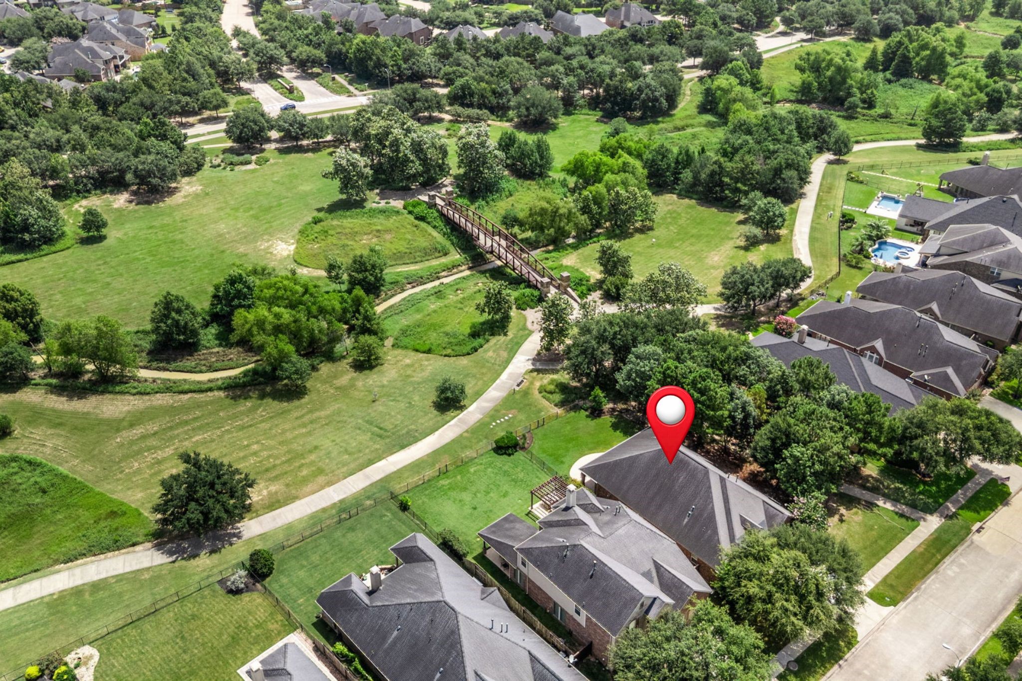 27642 Linden Ridge Lane Fulshear, TX 77441 - Photo 34 of 42 This view showcases the nature reserve behind the property, featuring a quaint bridge over the creek and scenic walking trails. The peaceful setting enhances the home’s privacy and offers a beautiful natural backdrop for everyday enjoyment. The home has been pinpointed for your reference, making it easy to identify its exact location within the scenic surroundings.