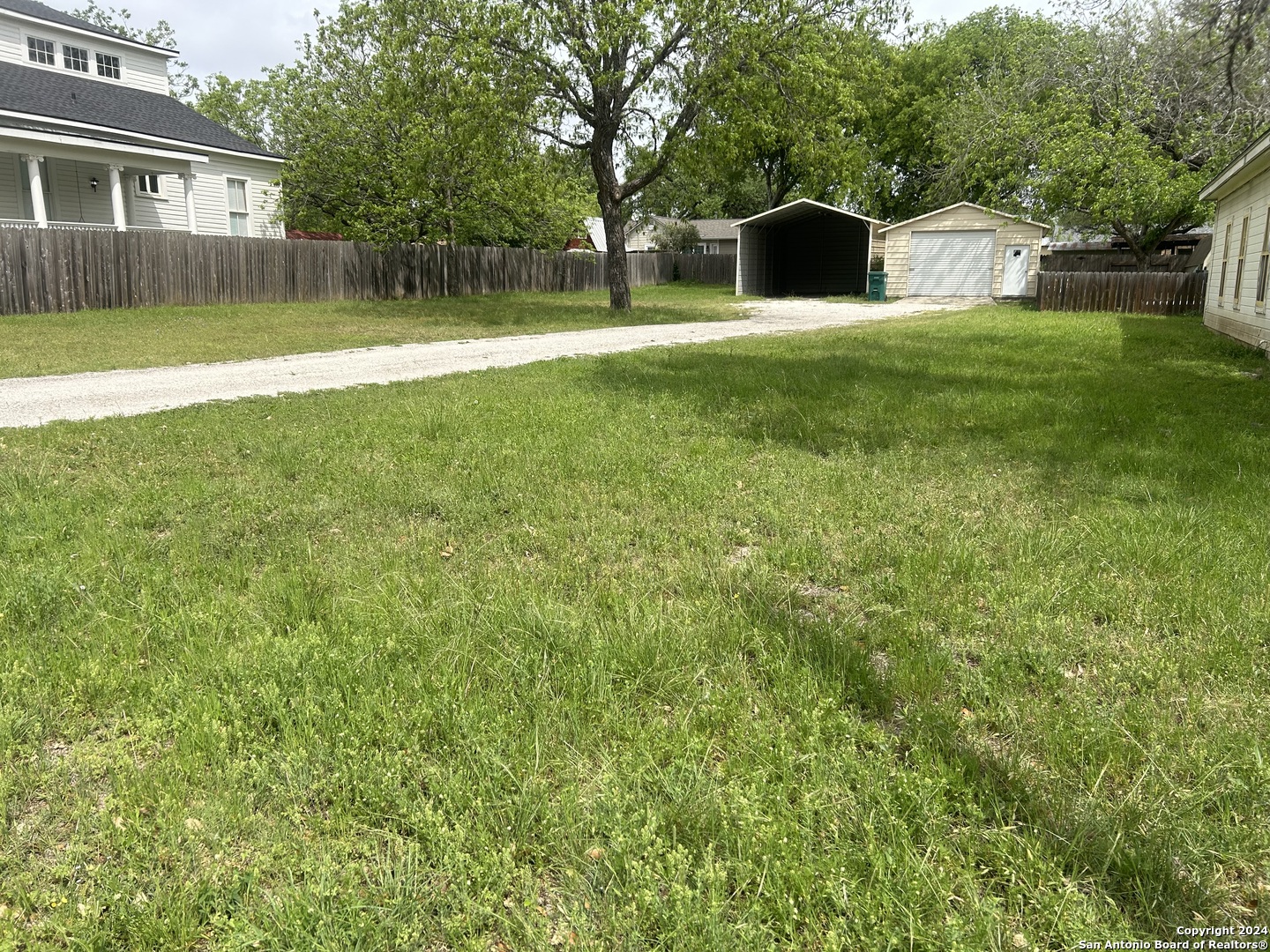 a view of a house with a yard and a large tree