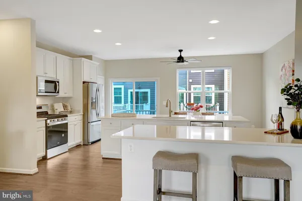 a open kitchen with granite countertop a stove top oven a sink dishwasher a dining table and chairs with wooden floor
