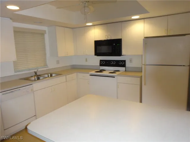 a kitchen with sink a microwave a stove and white cabinets