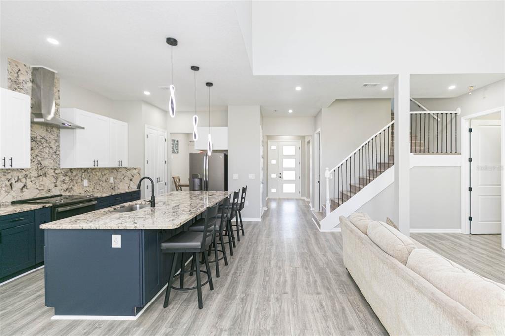 35369 Ruffing Road Dade City, FL 33523 - Photo 13 of 63 a large kitchen with stainless steel appliances kitchen island granite countertop a stove a sink a refrigerator and a dining table with wooden floor