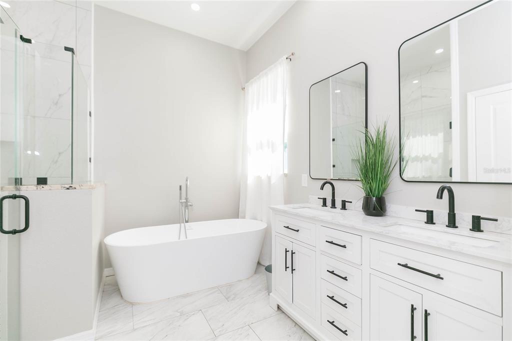 35369 Ruffing Road Dade City, FL 33523 - Photo 20 of 63 a bathroom with a white tub a double vanity sink a mirror and a shower