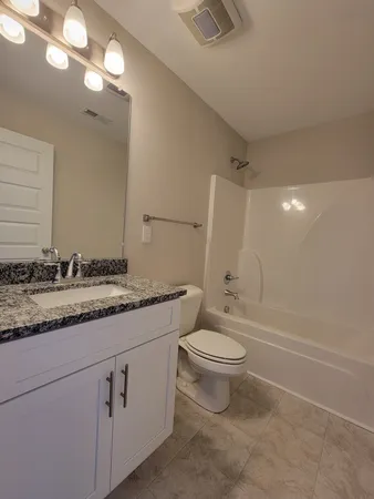 a bathroom with a granite countertop sink toilet a mirror and a bathtub