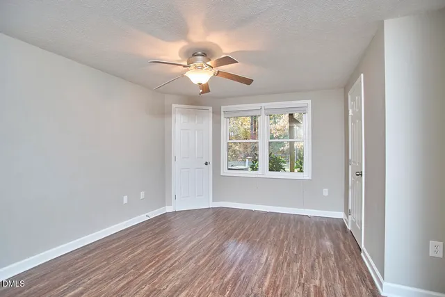 a view of an empty room with wooden floor and a window