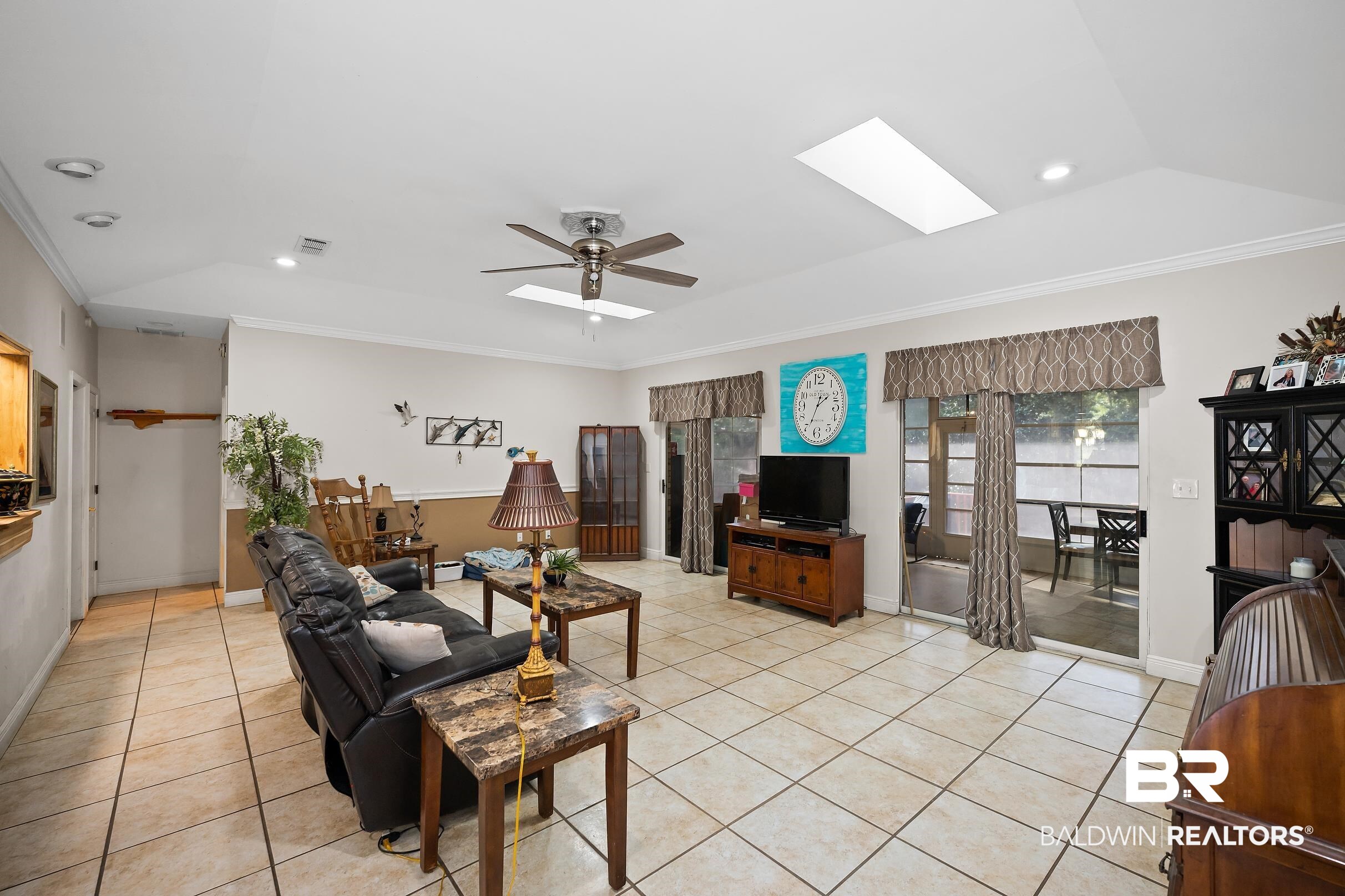 2674 Pine Ridge Drive Lillian, AL 36549 - Photo 5 of 42 Living area with crown molding, a skylight, light tile patterned flooring, lofted ceiling, and a ceiling fan