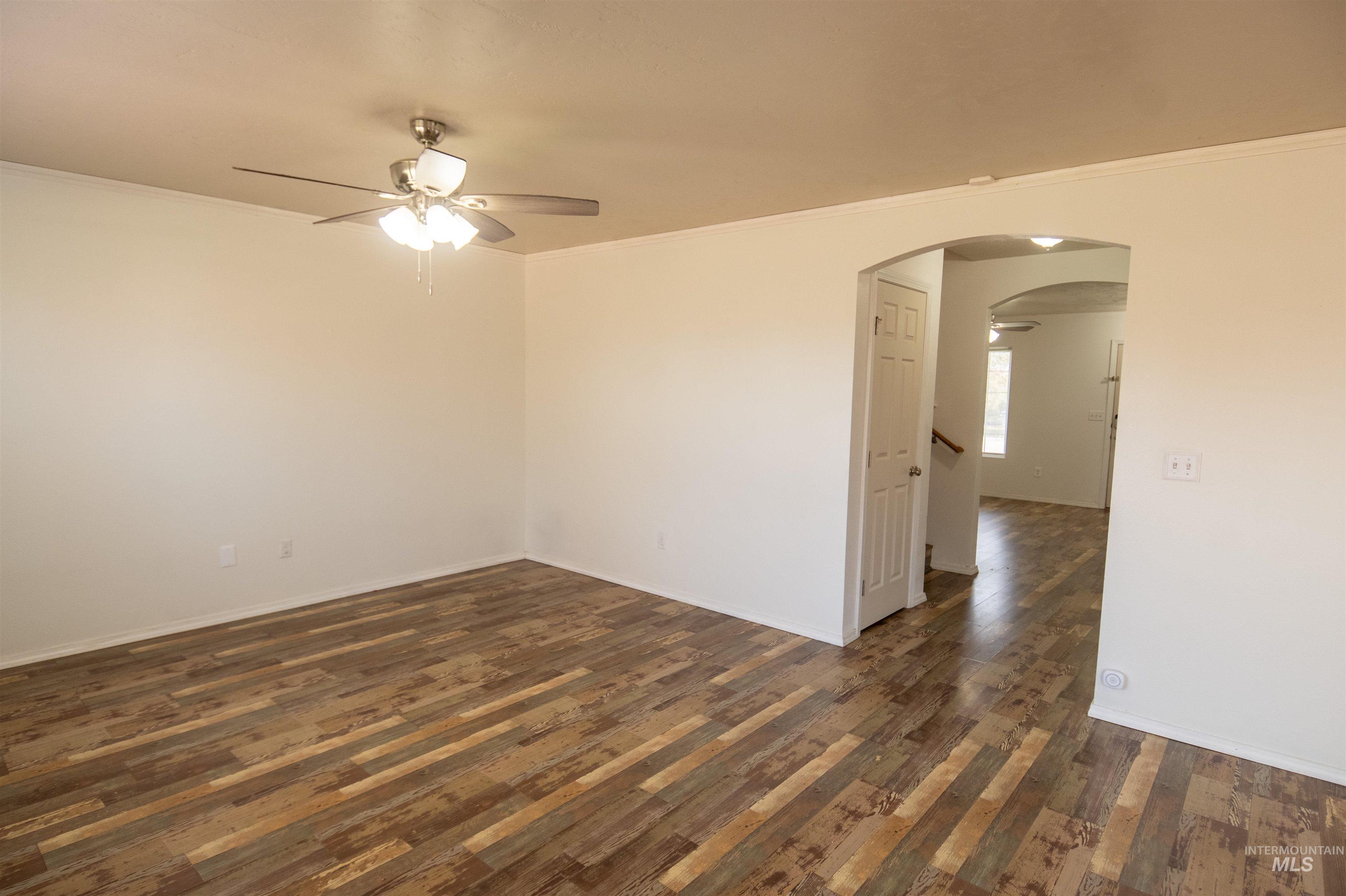 880 Southwest Independence Mountain Home, ID 83647 - Photo 15 of 50 Empty room featuring ceiling fan, ornamental molding, arched walkways, and dark wood-type flooring