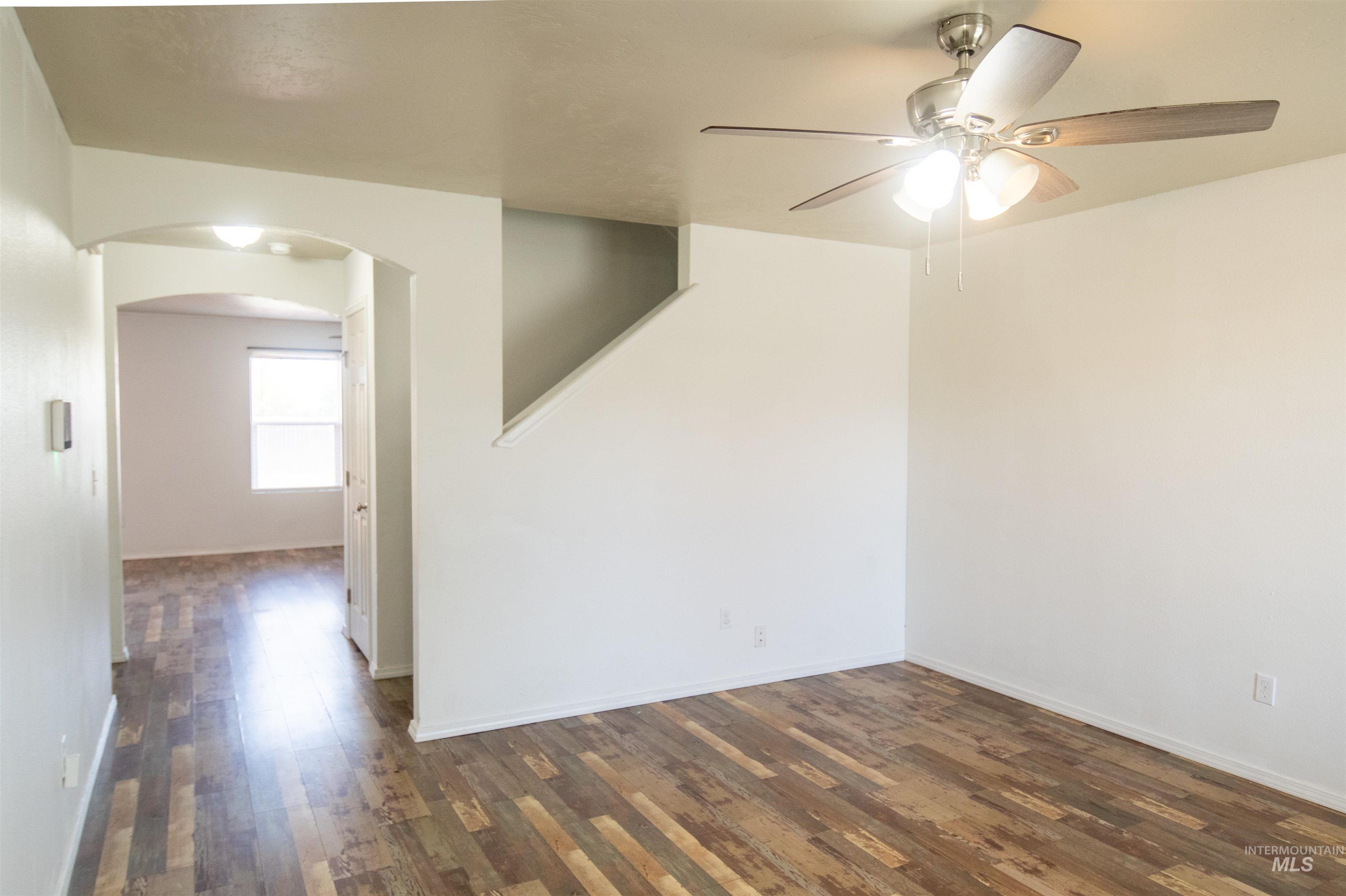 880 Southwest Independence Mountain Home, ID 83647 - Photo 7 of 50 Unfurnished room featuring dark wood-style floors, arched walkways, and a ceiling fan