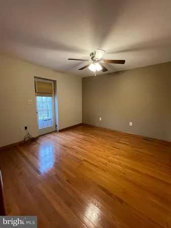 an empty room with wooden floor chandelier fan and windows
