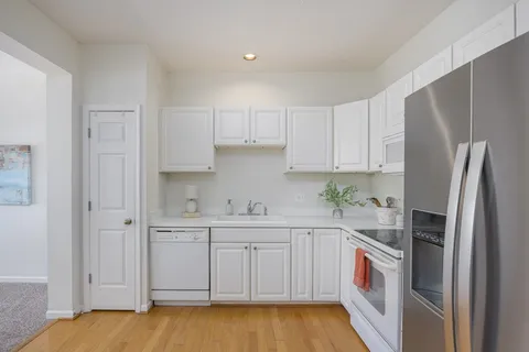 a kitchen with stainless steel appliances a dining table chairs and cabinets