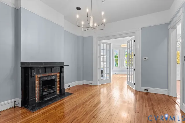 a view of an empty room with wooden floor fireplace and a window