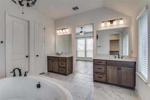 a spacious bathroom with a tub sink and mirror