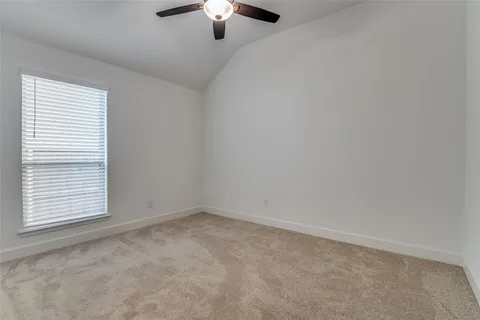 an empty room with a chandelier fan and windows