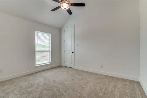 an empty room with a chandelier fan and windows