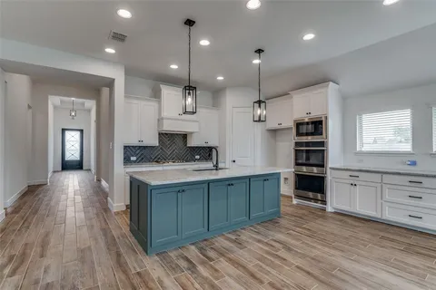 a large kitchen with kitchen island a sink stainless steel appliances and cabinets