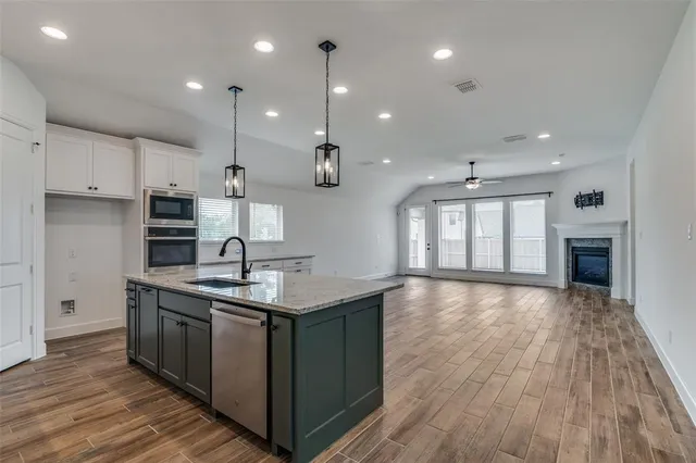 a kitchen with kitchen island granite countertop a sink stove and wooden floor
