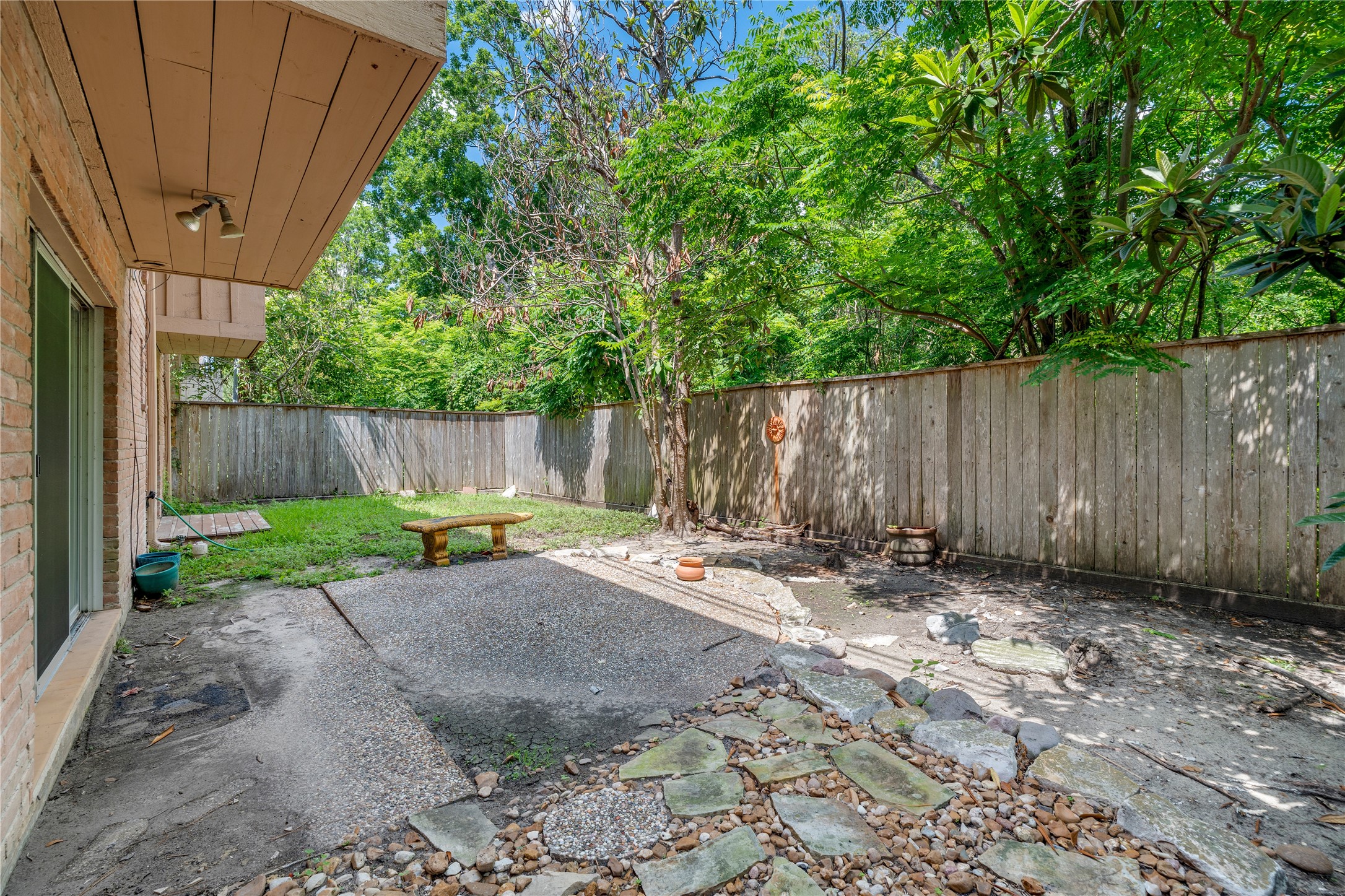 6303 Crab Orchard Road, Unit 3 Houston, TX 77057 - Photo 28 of 30 Step outside into your fully fenced, private backyard. This is a rare find—a mix of pebble-aggregate patio space for dining and lush green grass for pets or play. The towering trees provide a natural canopy, turning this yard into a cool, shaded retreat from the city.