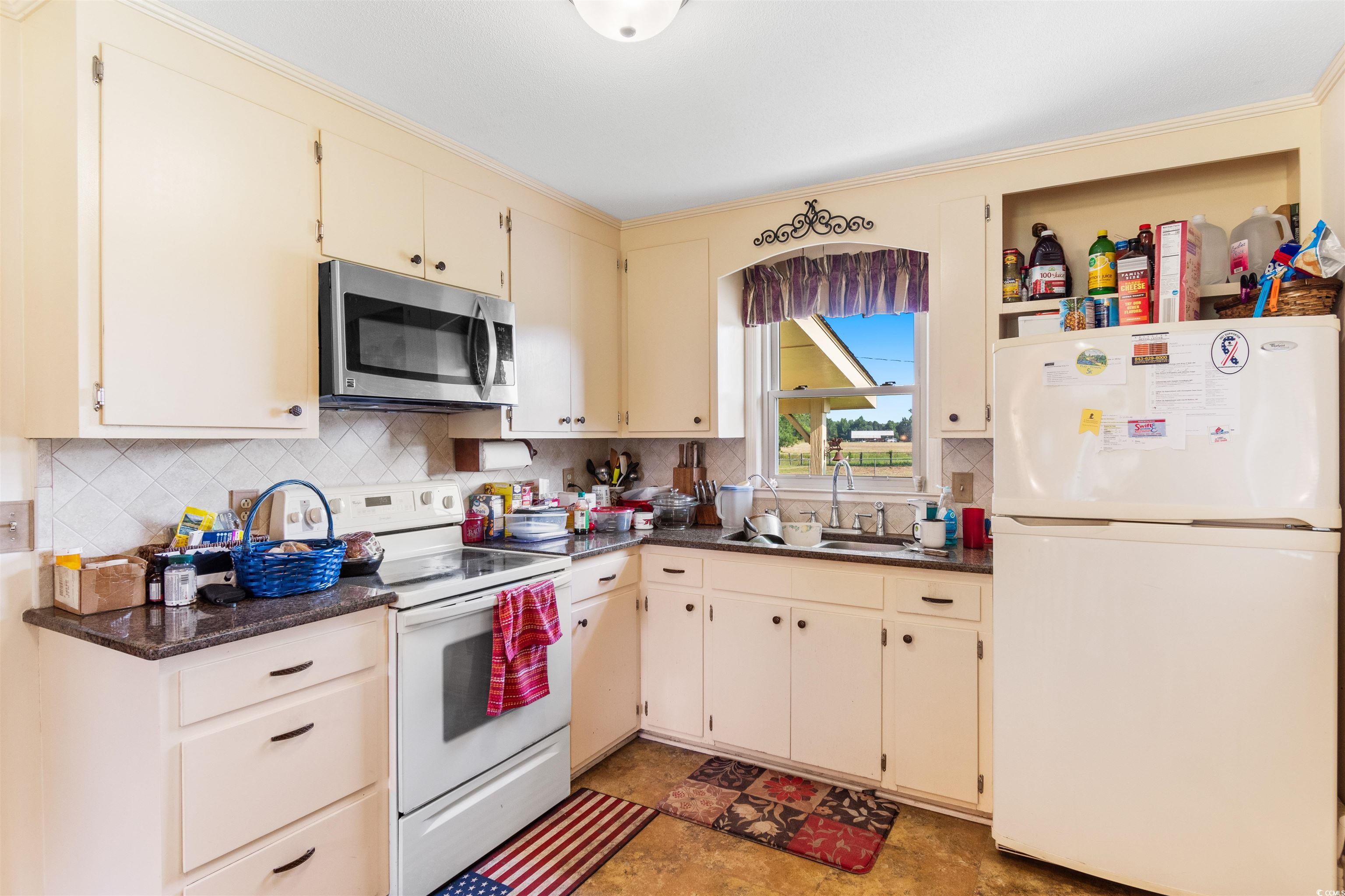 3101 Willow Creek Road Florence, SC 29505 - Photo 16 of 39 Kitchen featuring decorative backsplash, a sink, dark countertops, and white appliances
