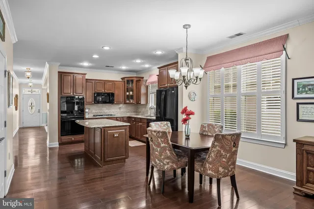 a kitchen with stainless steel appliances kitchen island granite countertop a dining table chairs and white cabinets