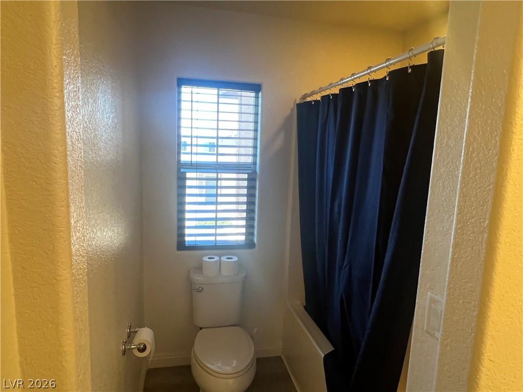 9581 Aberdeen Ridge Court Las Vegas, NV 89148 - Photo 18 of 25 A well-lit lavatory features a toilet beneath a window with blinds, adjacent to a shower.