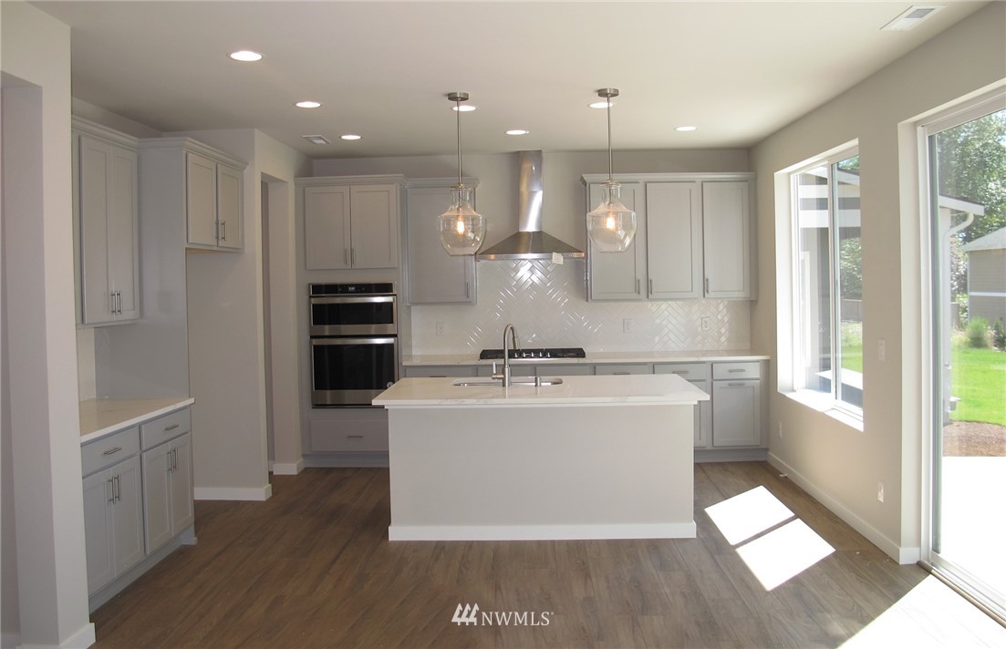109 215th Street Southeast, Unit 5 Bothell, WA 98021 - Photo 4 of 12 a large kitchen with stainless steel appliances kitchen island a large counter top and a wooden floors