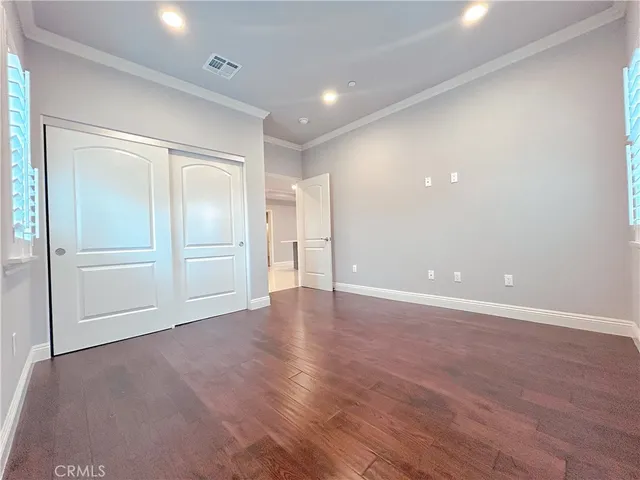 a view of an empty room with wooden floor and closet