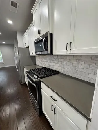 a kitchen with stainless steel appliances granite countertop a stove a sink and a microwave