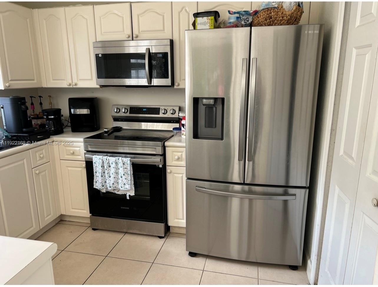 7317 Northwest 173rd Drive, Unit 104 Hialeah, FL 33015 - Photo 7 of 22 a kitchen with stainless steel appliances granite countertop a refrigerator a stove a microwave and cabinets