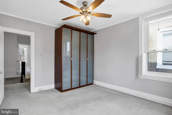 an empty room with chandelier fan and windows